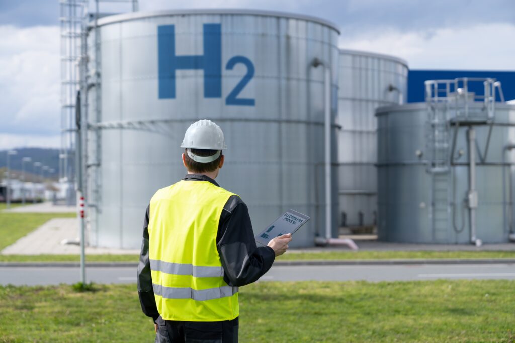 Worker with a helmet in front of hydrogen tanks